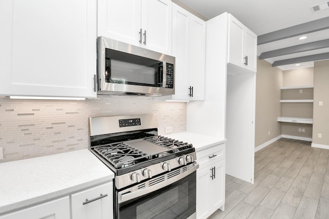 kitchen with white cabinets, appliances with stainless steel finishes, and backsplash