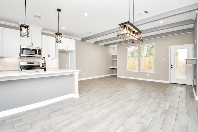 kitchen featuring white cabinetry, hanging light fixtures, and appliances with stainless steel finishes