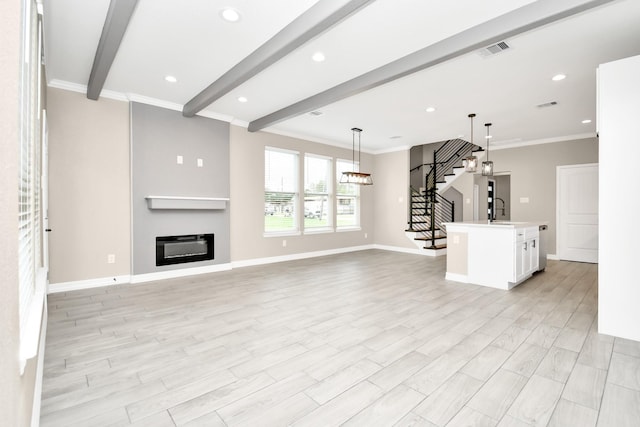 unfurnished living room featuring sink, beamed ceiling, ornamental molding, and light hardwood / wood-style flooring