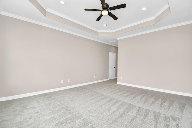 carpeted empty room featuring a raised ceiling, ceiling fan, and crown molding