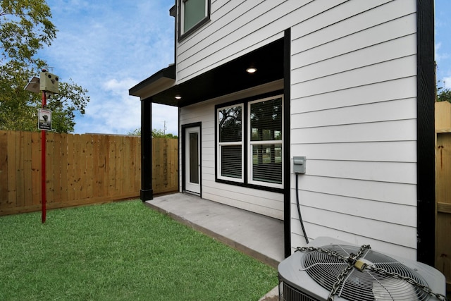 entrance to property featuring a lawn and cooling unit