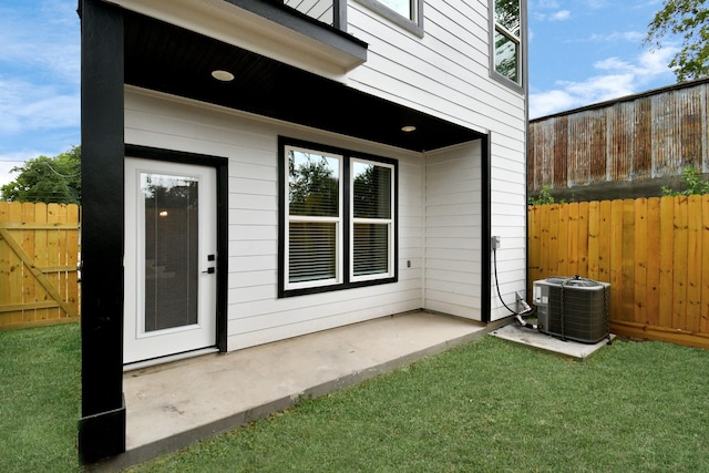 doorway to property with a lawn, cooling unit, and a patio