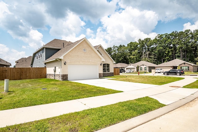 view of front of house featuring an attached garage, fence, stone siding, driveway, and a front lawn