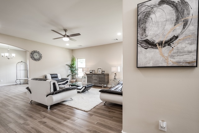 living room featuring hardwood / wood-style floors and ceiling fan with notable chandelier