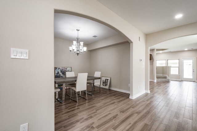 dining space with baseboards, visible vents, arched walkways, wood finished floors, and stairs