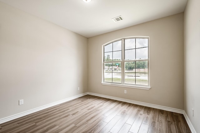 unfurnished room featuring wood finished floors, visible vents, and baseboards