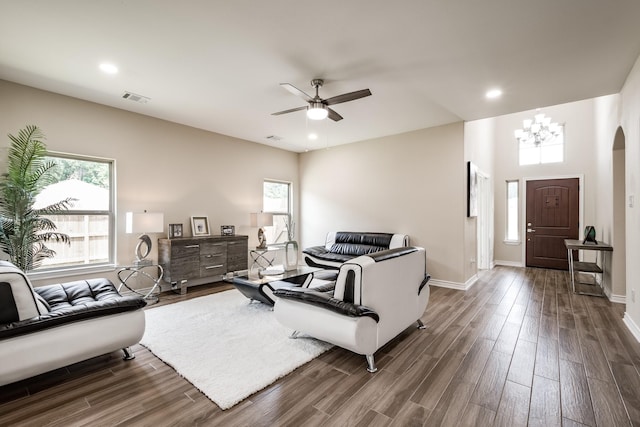 living room with ceiling fan with notable chandelier, arched walkways, visible vents, and wood finished floors