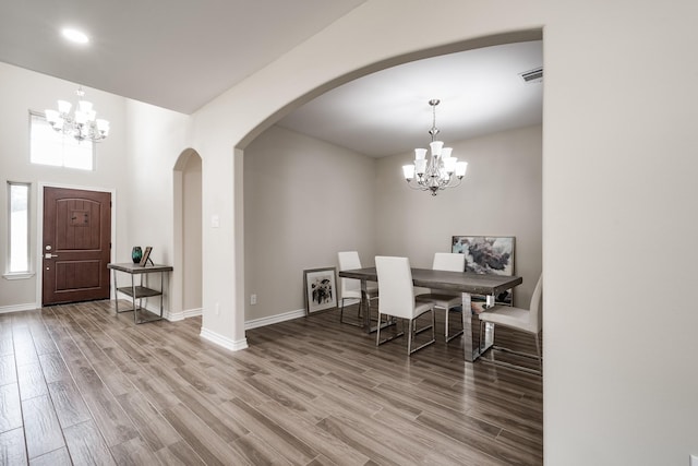 dining room featuring wood finished floors, baseboards, and an inviting chandelier