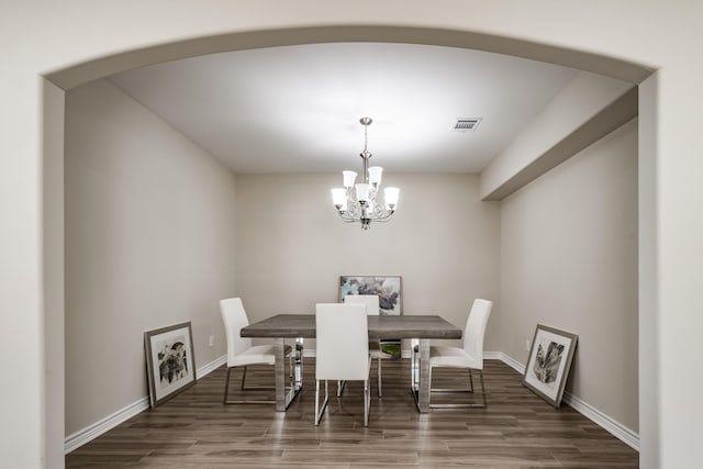 dining space with a notable chandelier, baseboards, visible vents, and wood finished floors