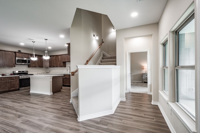 kitchen featuring a center island, hardwood / wood-style flooring, dark brown cabinets, range, and pendant lighting