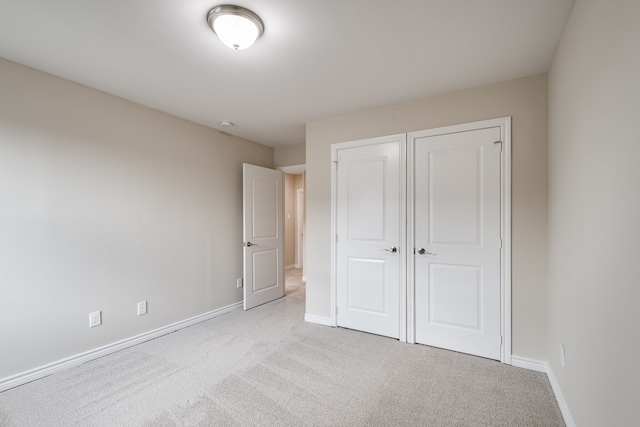 unfurnished bedroom with light carpet and a closet