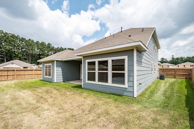 back of house with a shingled roof, a lawn, a fenced backyard, and central air condition unit