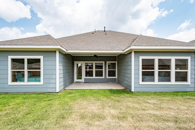 rear view of house with a ceiling fan, a patio area, roof with shingles, and a yard