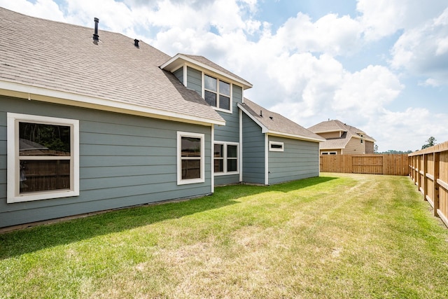 back of property featuring a fenced backyard, roof with shingles, and a yard