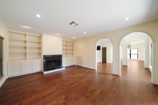 unfurnished living room featuring built in shelves and dark wood-type flooring