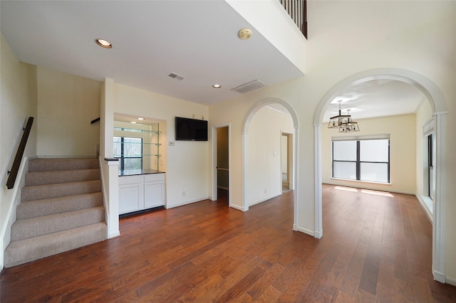 unfurnished living room with a chandelier and dark wood-type flooring