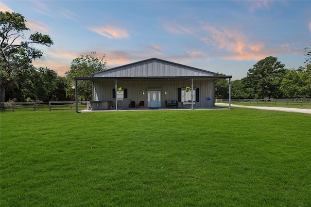 back house at dusk featuring a patio area and a lawn