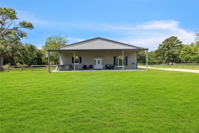 rear view of house with a patio, a lawn, and a hot tub