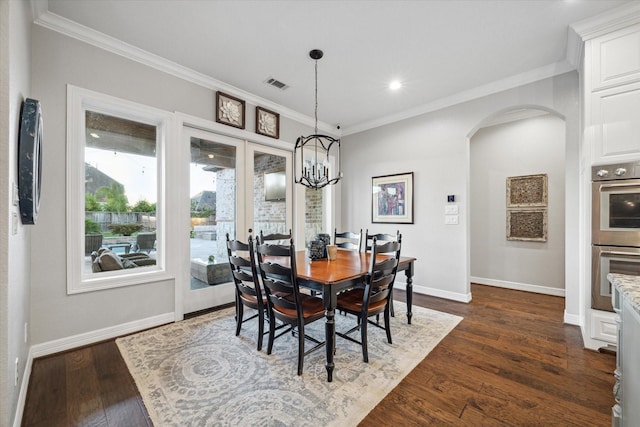 dining space featuring an inviting chandelier, french doors, crown molding, and dark wood-type flooring