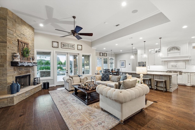 living room featuring ceiling fan, french doors, crown molding, hardwood / wood-style floors, and a fireplace