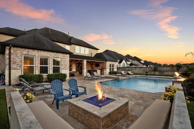 pool at dusk featuring a patio area, an in ground hot tub, and an outdoor fire pit