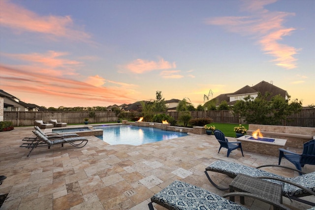 pool at dusk featuring a fire pit, an in ground hot tub, and a patio