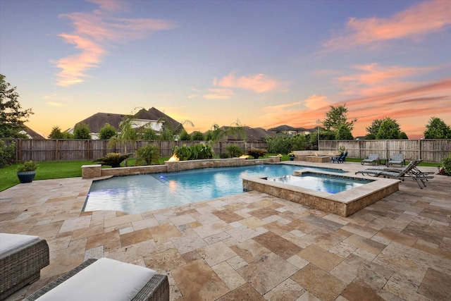 pool at dusk featuring an in ground hot tub, a yard, a patio, and pool water feature