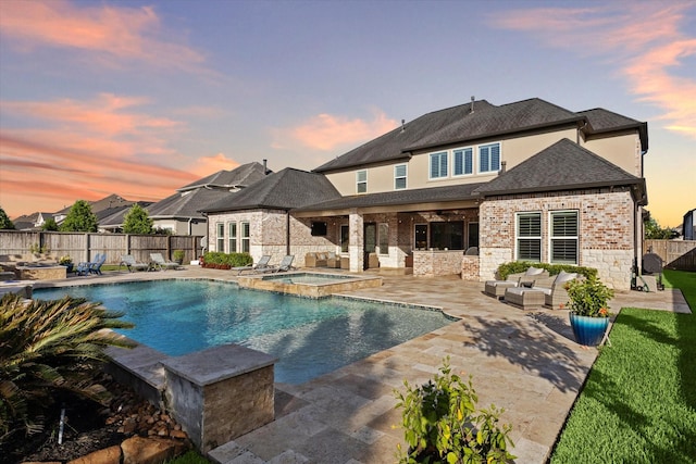 pool at dusk with an outdoor living space, a patio area, and an in ground hot tub