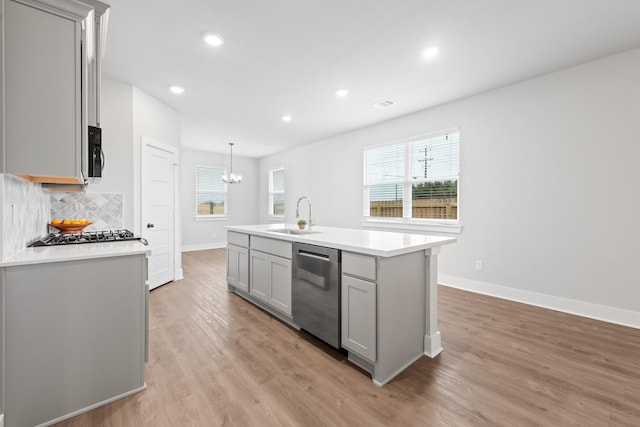 kitchen with gray cabinetry, dishwasher, sink, pendant lighting, and a center island with sink