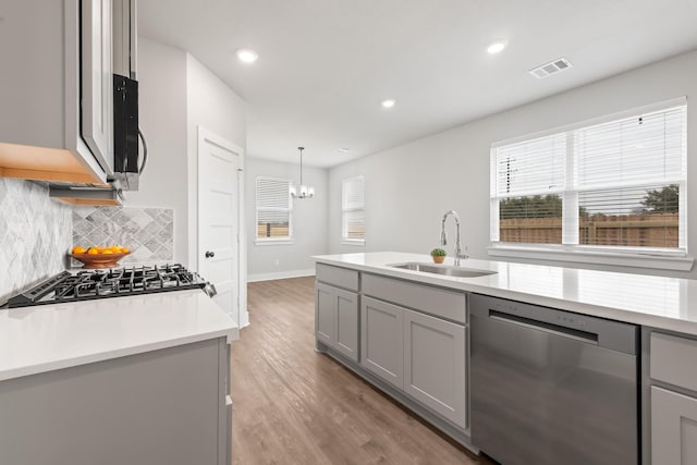 kitchen with appliances with stainless steel finishes, gray cabinetry, pendant lighting, and sink