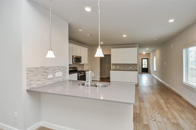 kitchen featuring hanging light fixtures, sink, white cabinets, and stainless steel appliances