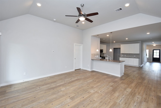 unfurnished living room featuring ceiling fan, sink, vaulted ceiling, and light wood-type flooring