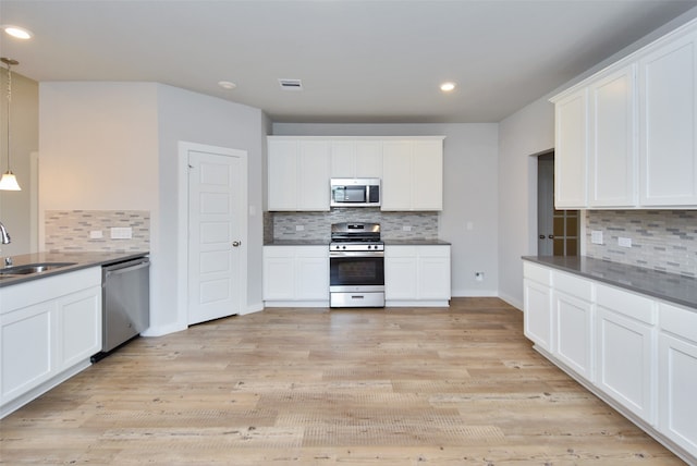 kitchen with sink, white cabinetry, stainless steel appliances, and hanging light fixtures