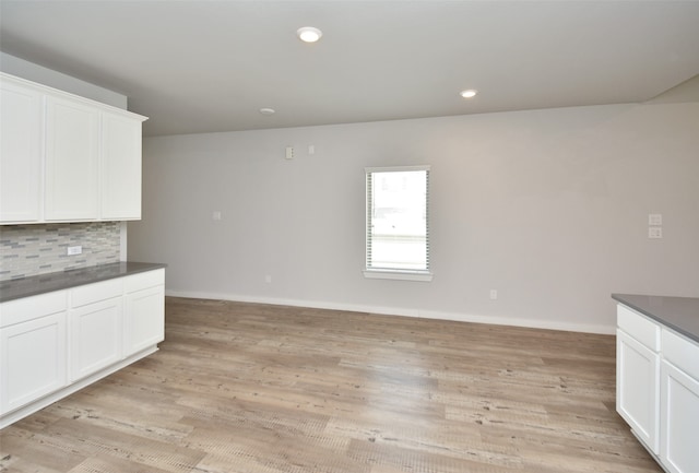 kitchen with tasteful backsplash, white cabinets, and light hardwood / wood-style floors