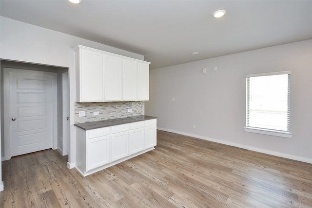 kitchen featuring backsplash, light hardwood / wood-style floors, and white cabinetry