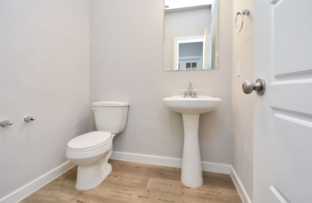 bathroom featuring wood-type flooring, toilet, and sink