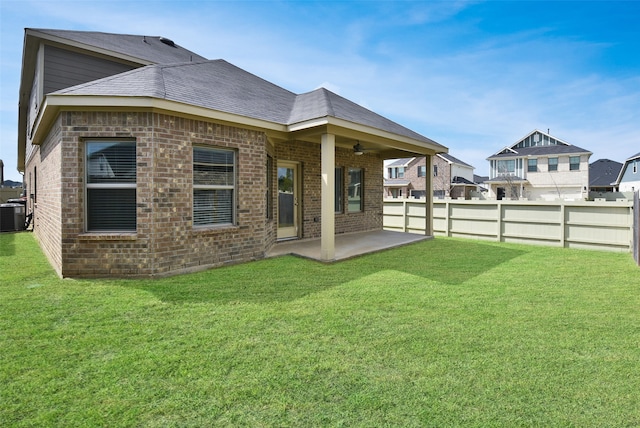 rear view of house featuring a yard, central AC unit, and a patio area