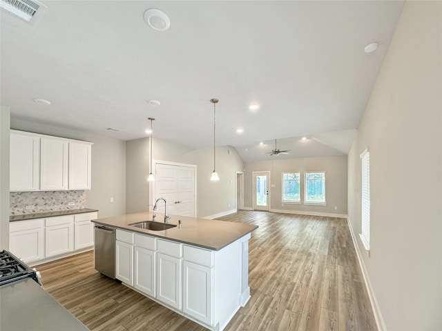 kitchen with stainless steel dishwasher, light wood-type flooring, sink, vaulted ceiling, and backsplash