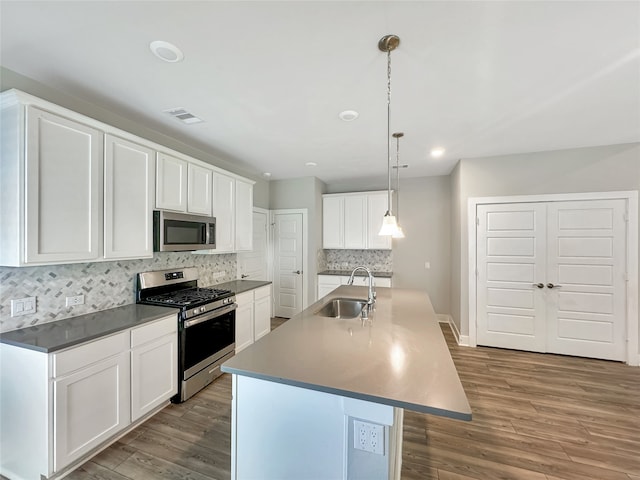 kitchen featuring appliances with stainless steel finishes, light hardwood / wood-style flooring, white cabinets, sink, and an island with sink