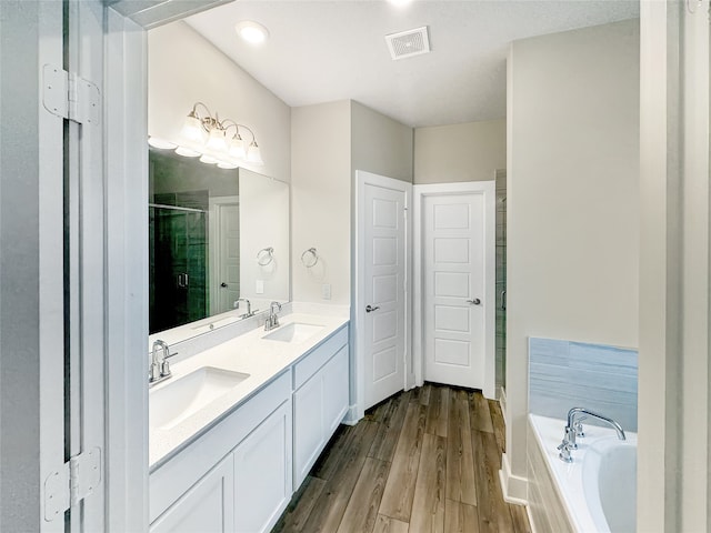 bathroom featuring separate shower and tub, wood-type flooring, and double sink vanity