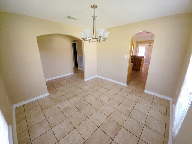 empty room featuring light tile patterned flooring and an inviting chandelier