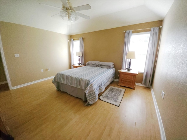 bedroom featuring ceiling fan, light hardwood / wood-style floors, lofted ceiling, and multiple windows