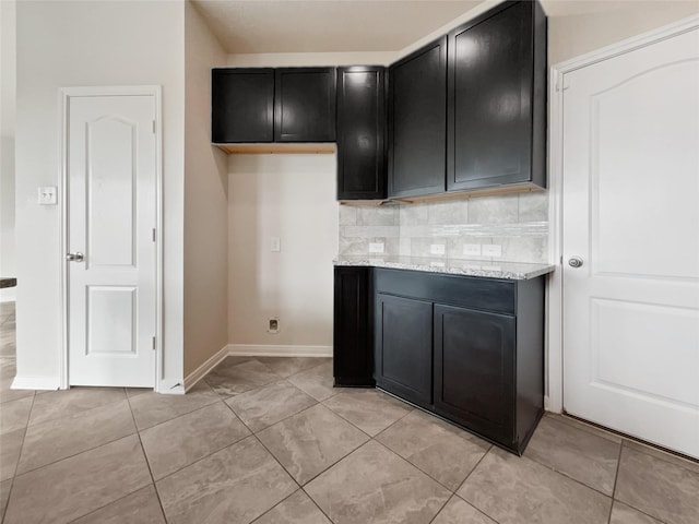 kitchen with tasteful backsplash, light tile patterned flooring, and light stone counters