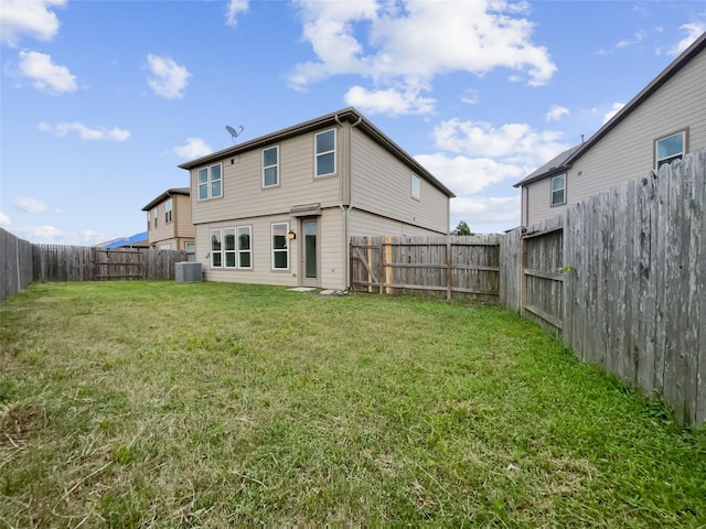 rear view of property featuring a yard and central air condition unit