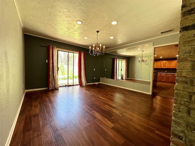 empty room featuring an inviting chandelier, ornamental molding, dark hardwood / wood-style flooring, and a textured ceiling