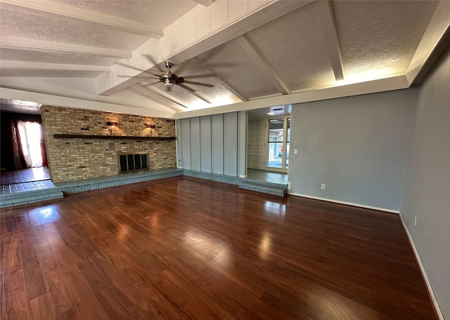 unfurnished living room with a brick fireplace, wood-type flooring, lofted ceiling with beams, and a textured ceiling