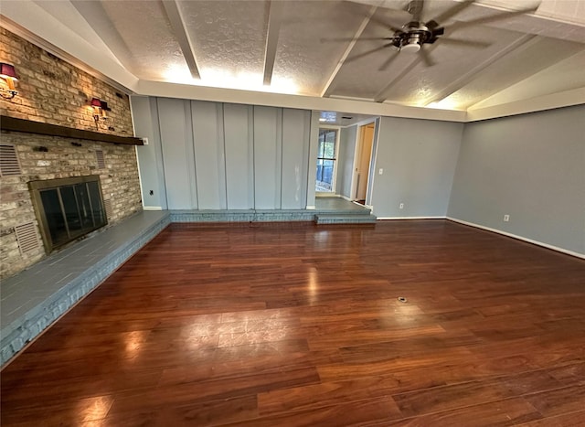 unfurnished living room featuring vaulted ceiling, a brick fireplace, a textured ceiling, and dark hardwood / wood-style flooring