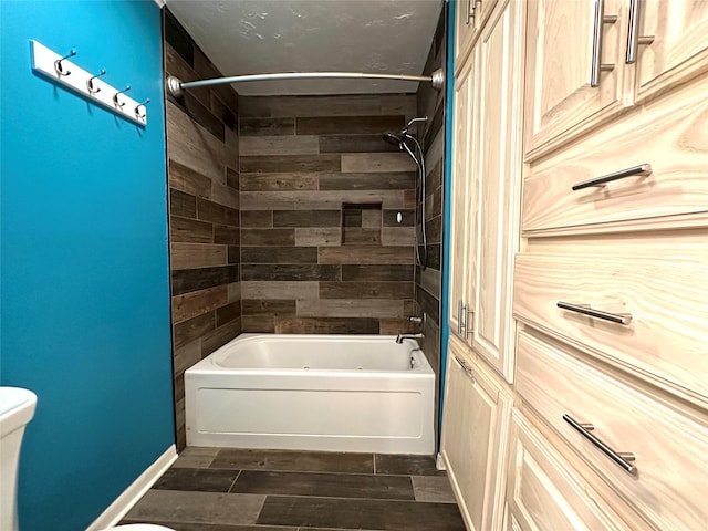 bathroom featuring tiled shower / bath combo and toilet