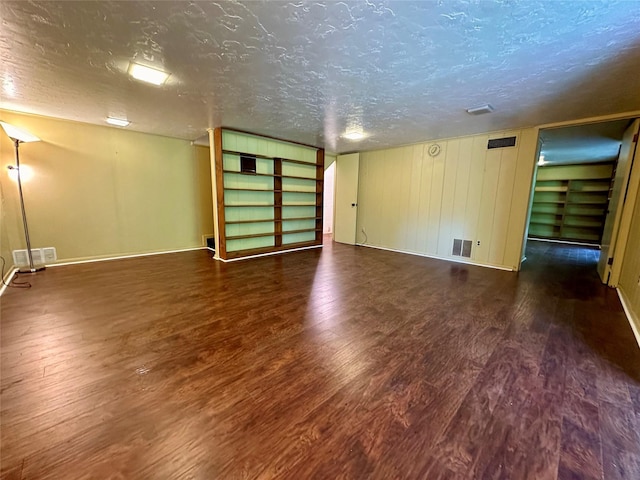 spare room featuring dark wood-type flooring and a textured ceiling