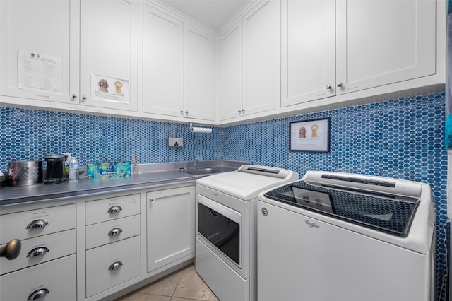 laundry area featuring sink, washer and clothes dryer, cabinets, and light tile floors